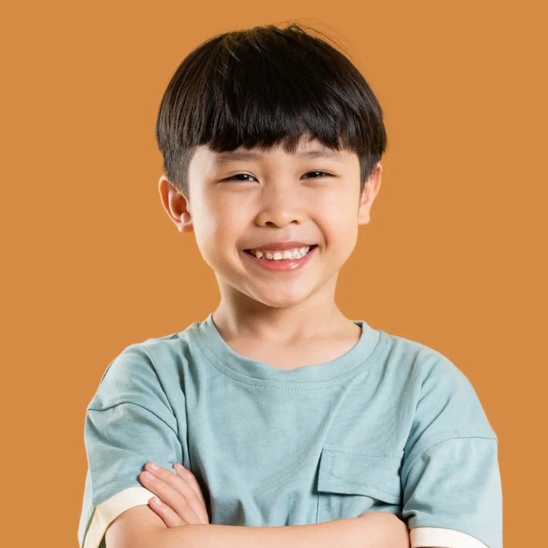 A smiling child standing with their arms folded