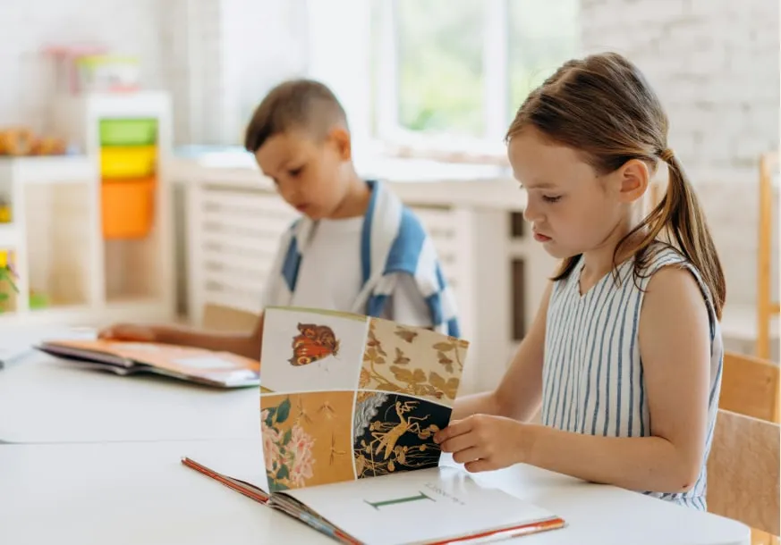 Two children reading a picture book together at a table